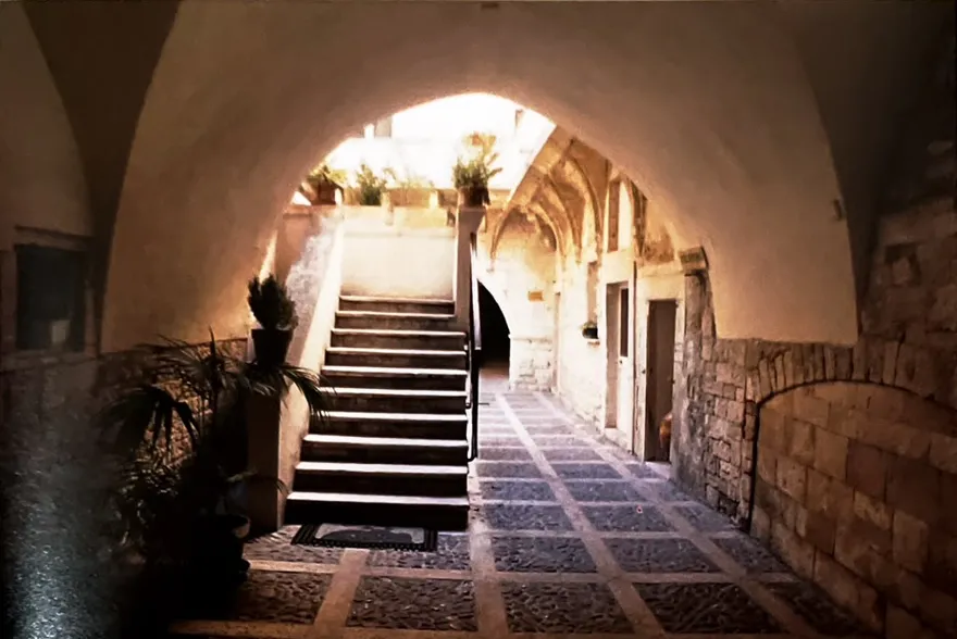 Vicoli di Bari Vecchia con archi in pietra calcarea e balconi fioriti
